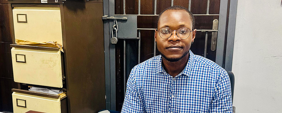 Noel, ein Teilnehmer des ARRIVES-Programms, sitzt an seinem Schreibtisch in seiner neuen Position im Finanzwesen in Nigeria, die er dank Jobcoaching und Unterstützung durch ARRIVES erhalten hat.