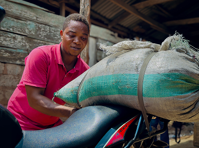 Dominic, ein Teilnehmer des ARRIVES-Programms, lädt im Rahmen seiner Tätigkeit als Schweinezüchter in Nigeria landwirtschaftliche Bedarfsartikel auf sein Motorrad.