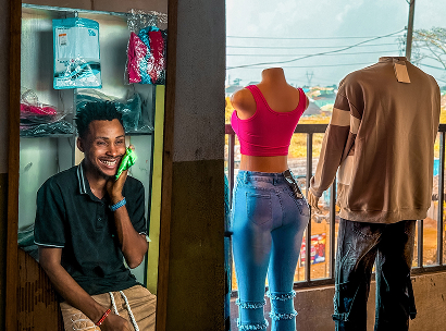 Chris, ein Teilnehmer des ARRIVES-Programms, lächelt, während er in seinem neuen Modeunternehmen sitzt, das er mit Unterstützung von ARRIVES in Nigeria gegründet hat.
