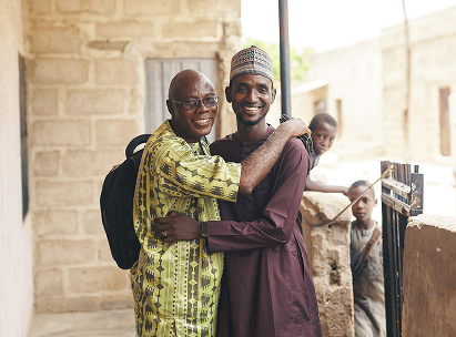 Umar, ein Teilnehmer des ARRIVES-Programms, steht und umarmt einen der ARRIVES-Coaches, der ihm nach seiner Rückkehr aus Deutschland nach Nigeria dabei geholfen hat, ein Solarenergieunternehmen zu gründen.